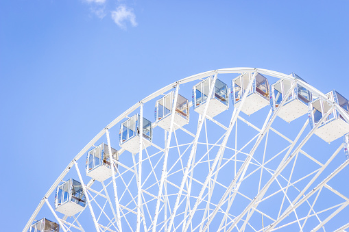Ferris wheel on a blue sky. Amusement park. Empty ferris wheel on sunny day in Kyiv, Ukraine. Summer recreation. Leisure activity. Big circle. Vintage carousel on blue sky. Outdoors attraction.