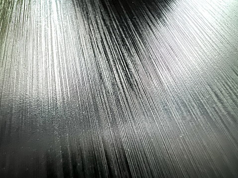 A macro image of a shiny, black and fine plastic with traces.