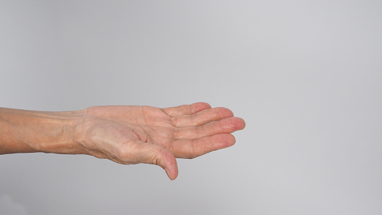 Man's hand with extended index finger against a gray wall  background