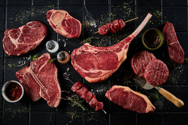 Raw beef steaks cutlets and shashlik with spices Top view set of steaks consisting of t bone sirloin ribeye tomahawk with skewers and burger patties composed with spatula spices and salt meat stock pictures, royalty-free photos & images