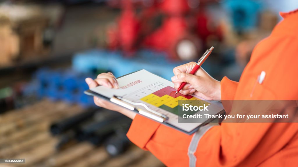 Evaluate the risk assessment matrix table at "High risk" level. Action of a person is using ballpoint pen to marking on the risk assessment matrix table at "High risk" level. Industrial or business working action scene photo. Close-up and selective focus. Risk Stock Photo