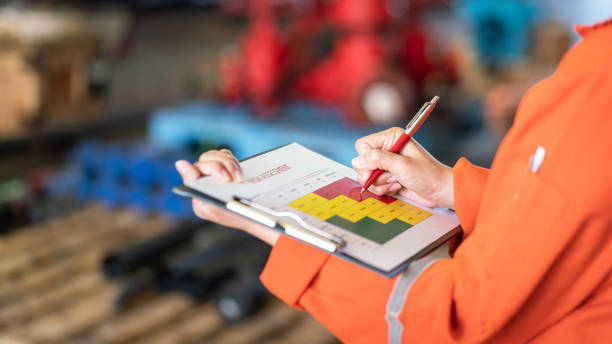 Evaluate the risk assessment matrix table at "High risk" level. Action of a person is using ballpoint pen to marking on the risk assessment matrix table at "High risk" level. Industrial or business working action scene photo. Close-up and selective focus. unsafe workplace stock pictures, royalty-free photos & images