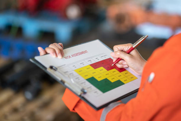 Evaluate the risk assessment matrix table at "High risk" level. Action of a person is using ballpoint pen to marking on the risk assessment matrix table at "High risk" level. Industrial or business working action scene photo. Close-up and selective focus. health and safety stock pictures, royalty-free photos & images