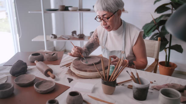 istock Asian elderly woman enjoying pottery work at home. A female ceramicist is making new pottery in a studio. 1403668024