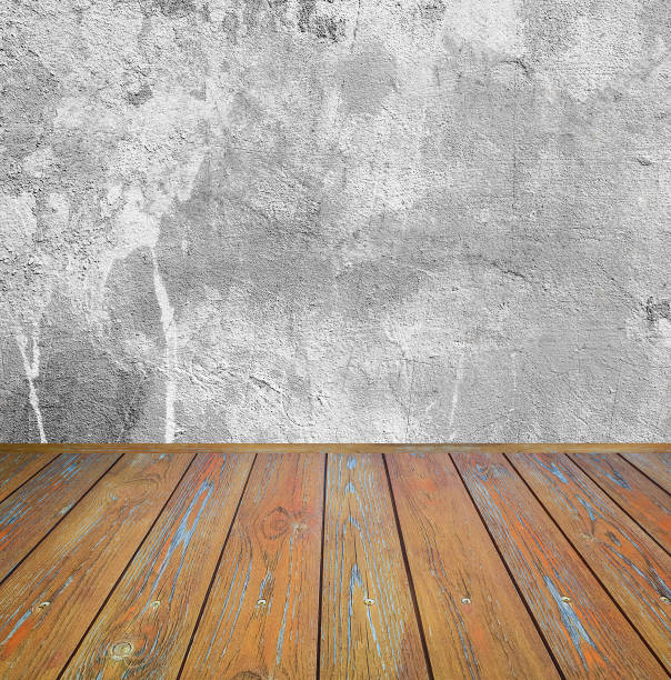 Room interior: grey damaged cement wall with brown wooden floor