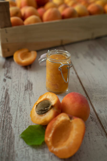 Female hands cutting fresh sweet peaches to make peach jam. Female hands cutting fresh sweet peaches. Peaches whole fruits leaves, half peach, peach slices on white wooden kitchen table. Recipe making peach jam, cooking peach dessert on cutting board. Flat lay cottagecore stock pictures, royalty-free photos & images