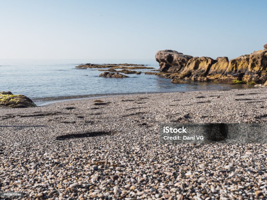 Small stone beach shore in the mediterranean sea on the Costa del Sol. Transparent water and eroded rocks in Manilva Andalusia Stock Photo