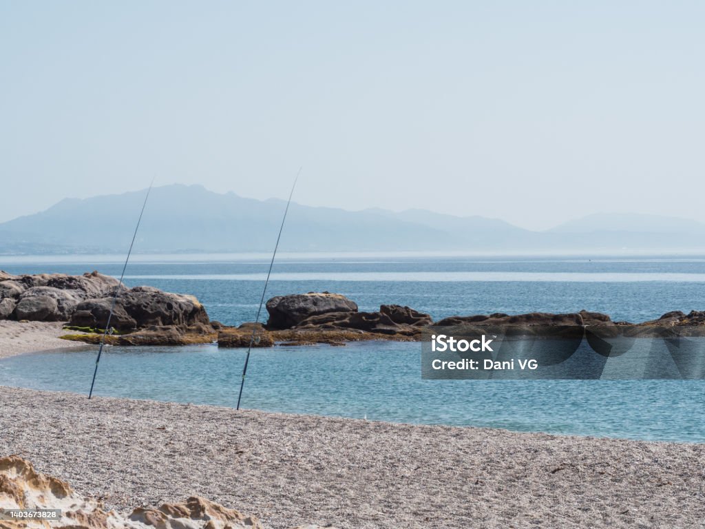 Fishing rods on the shore of the beach in sunny day by the sea. Fishing, relax and vacation concept Adventure Stock Photo