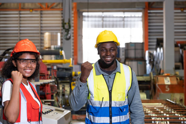 istock African mechanical engineer team, wearing safety equipment. While doing machine maintenance and safety control while work inside of factory area. With blurred background of heavy machine. 1403674463