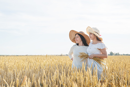 Freedom, friendship concept. Two smiling female friends in white shirts in the wheat field