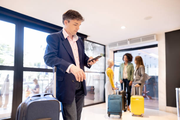 istock Young businessman with luggage using his cellphone at hotel lobby 1403674860