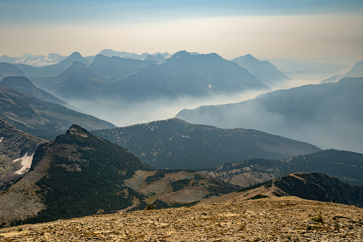 Wildfire smoke fills up valley in vast mountains of Glacier National Park, Montana, USA on a hot dry day of summer. Climate change impact. Global warming