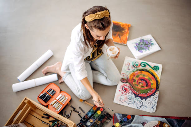 One young woman, beautiful artist, painting on the floor at home.