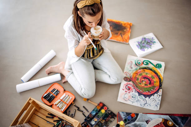 One young woman, beautiful artist, painting on the floor at home.