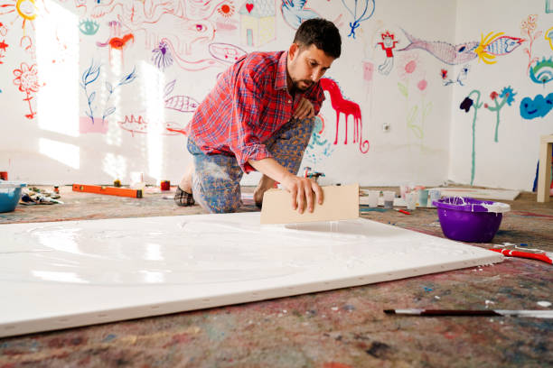 istock Adult man spreading paint across canvas 1403680143