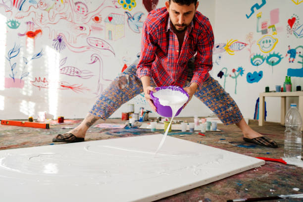 istock Mid adult man spreading paint on canvas 1403680164