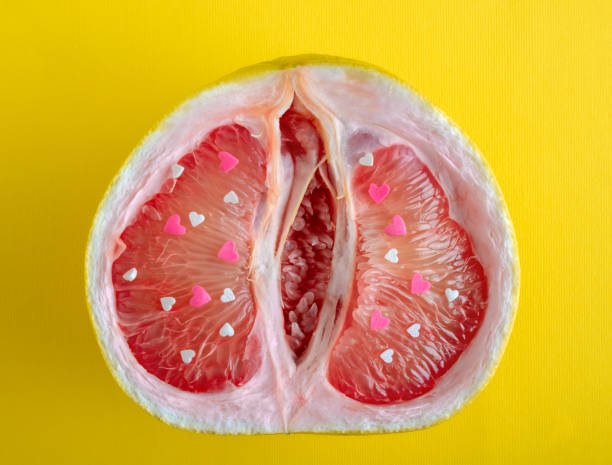 Top view grapefruit half with red and white hearts on yellow background. stock photo