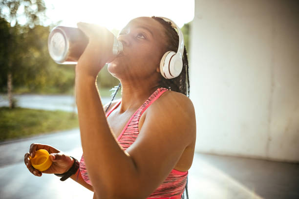 istock Happy sportswoman drinking water in park 1403683392