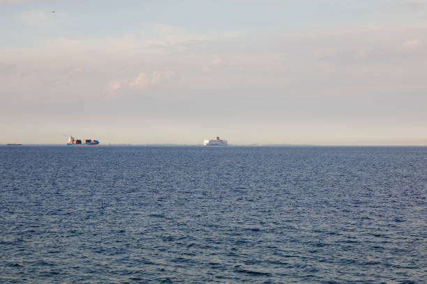 Gdynia, Poland - May 25, 2022: From the shore in Gdynia, a container ship and a passenger ferry are visible in the distance on the horizon in the Bay of Gdansk on the Baltic Sea