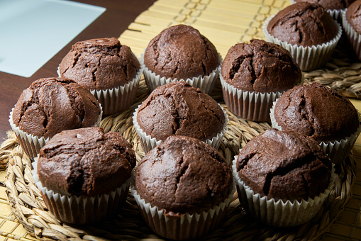 Close-up homemade chocolate muffins with chocolate toppings on wooden table
