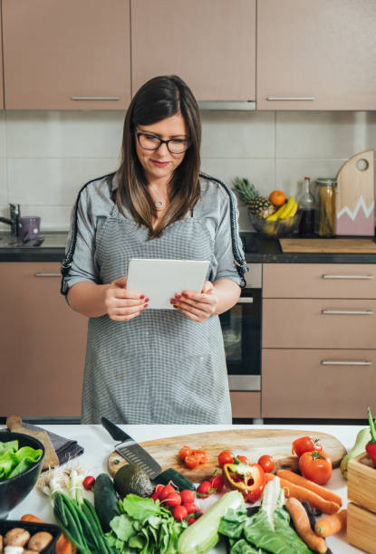 istock Smiling Woman Reading Recipe On A Digital Tablet While Cooking Lunch In The Modern Kitchen 1403689282