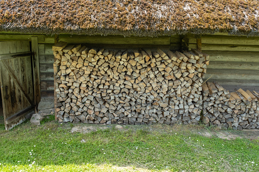 Fuel for stove heating. Country life. Wooden firewood stacked wall. Natural wood background. Firewood stacked in several rows.