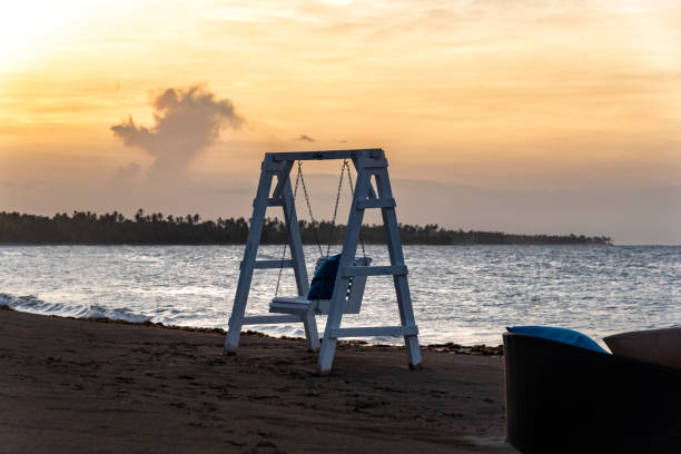 Caribbean beach with swing at sundown stock photo