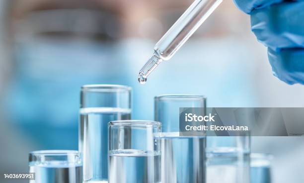 Closeup Gloved Hand Adds Liquid From Pipette To One Of Test Tubes Unrecognizable Masked Man In Blur In Background Concept Of Science Development Genetic Research Pharmaceutical Technology Or Biotech Science Stock Photo - Download Image Now