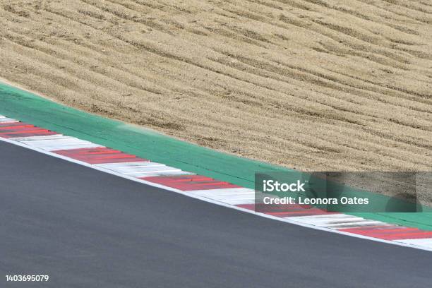 A Section Of A Car Race Track With A Sandy Gravel Trap To Slow The Cars Down A Red And White Chevron Marking A Corner With Green Tarmac On The Inside And Grey Tarmac On The Outside Stock Photo - Download Image Now