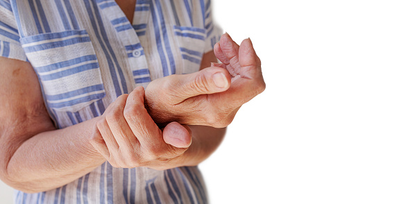 Close-up of female hands holding a painful wrist caused by long-term work at a computer, laptop. Carpal tunnel syndrome, arthritis, neurological disease concept. Hand numbness