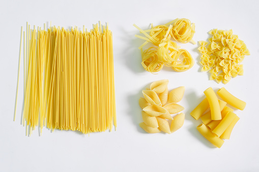 Italian spaghetti, farfalle, conciglioni, rigatoni and tagliatelle in groups on a white plate. Assorted. View from above. Daylight