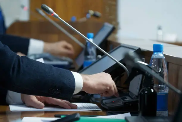 Photo of The politician's hand is extended to the voting device. The concept of making a decision and adopting amendments to legislation. Selective focusing