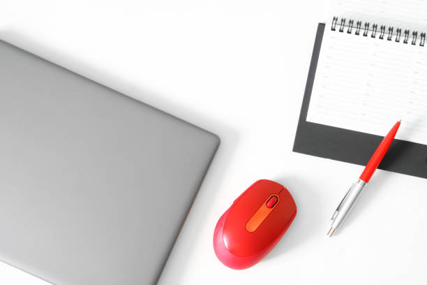 istock Gray laptop or ultrabook, red computer mouse, fountain pen and diary on a white table. Workplace and business planning concept. Free space for an inscriptio 1403699363