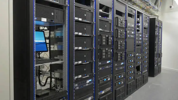 Photo of Many powerful servers running in the data center server room. Many servers in a data center. Many racks with servers located in the server room. Bright display a plurality of operating equipment.