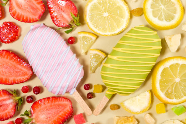 Two ice creams on a sticks - strawberry and lemon on a beige background.