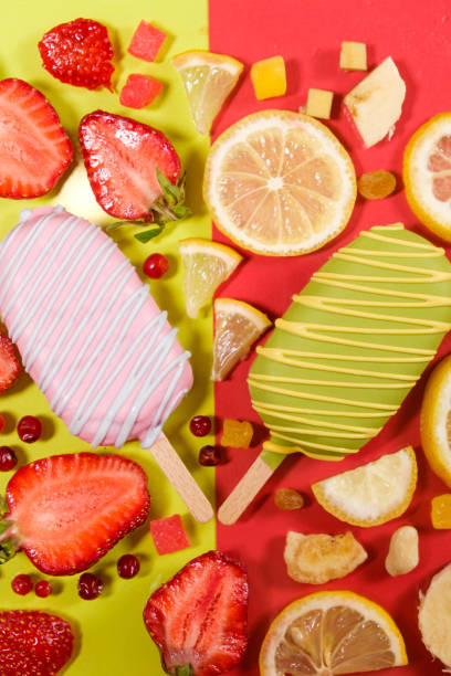 Two ice creams on a sticks - strawberry and lemon on a yellow and red background. Summer fruit desserts.
