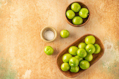 green plums, beautiful and delicious ripe green plum fruits served with salt on table with selective focus. top view fresh and healthy fruits. healthy summer food concept photo