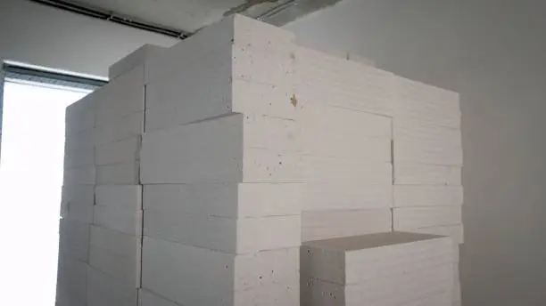 Building blocks for the construction of walls and partitions. Advertising of foam concrete blocks for building walls. Aerated concrete building blocks in a package. Construction of walls from gypsum blocks. Stacks of blocks at the construction site.