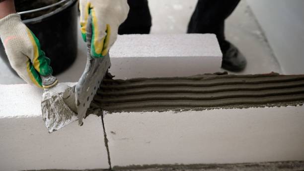 istock Building walls, placing bricks on a construction site, engineering and building concepts. Mason performs an internal masonry blocks aerated concrete. 1403706275