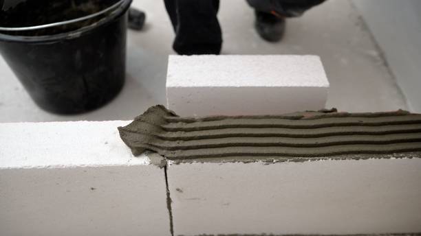 istock One block is put on another. The builder builds a wall of concrete blocks. Masonry worker make concrete wall by cement block and plaster at construction site. A worker erects a wall of aerated concrete blocks. 1403706293