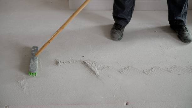 istock A worker sweeps white concrete dust from the floor. Garbage collection after repair work at home. A worker brushes the floor after repair. 1403707491