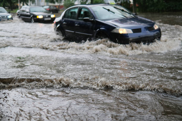 circulation automobile dans la rue inondée sous une pluie battante. - flood photos et images de collection