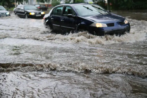 Car traffic on the flooded city street during heavy rain, heavy rainfall. Disaster flood, deluge. Water flow