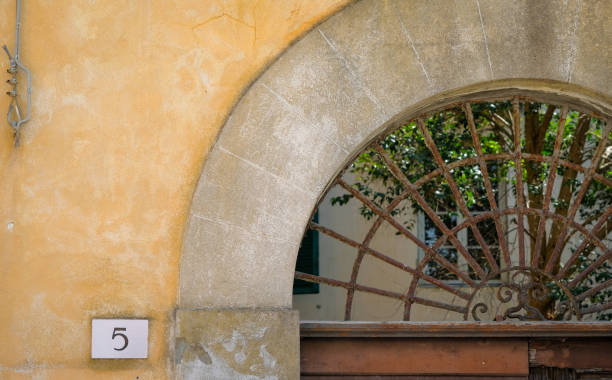 istock Rusted iron grate set in arched doorway with simple address on plaster wall. 1403709192