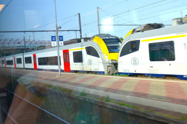 Aarschot, Vlaams-Brabant, Belgium - June 18, 2022: motion blur platform Aarschot railway station, view from inside windscreen moving train, on waiting passenger train on platform track 5