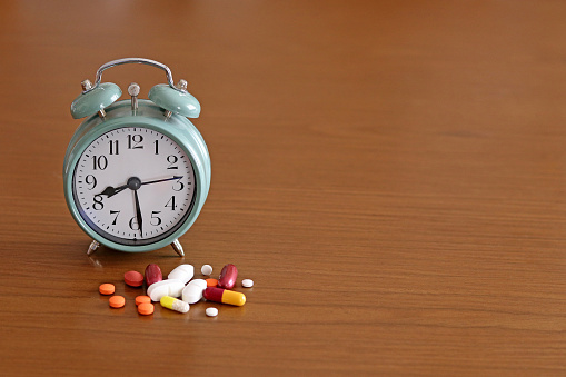 Medicines or pills next to an alarm clock on a white background. Concept of time to take care of health. Antimicrobial resistance