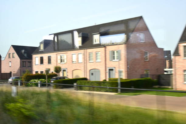 Heist-Op-Den-Berg, Vlaams-Brabant, Belgium - June 18, 2022: blurred view photographed from inside a moving train on Flemish landscapes. Real estate project  semi-detached red brick housing with a front garden. typical Belgian saying brick in the stomach. 70% of Belgians are owner their house mostly with a mortgage
