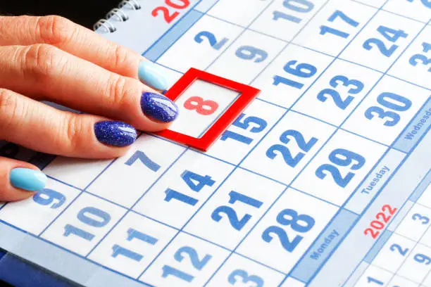 Photo of A woman's hand with a manicure points to the calendar with the date of the international women's holiday March 8 highlighted in red
