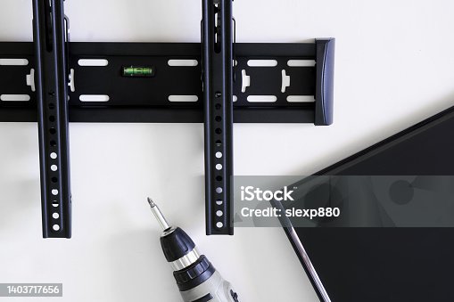 istock TV wall mount bracket, monitor or TV and electric drill. The concept of mounting a TV or computer monitor on the wall using a bracket. Bubble level 1403717656