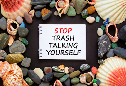 Stop trash talking yourself symbol. Concept words Stop trash talking yourself on a beautiful black background. Sea stones and seashells. Psychological and stop trash talking yourself concept. Copy space.